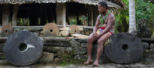 Yapese elder man sitting with stone money at village center